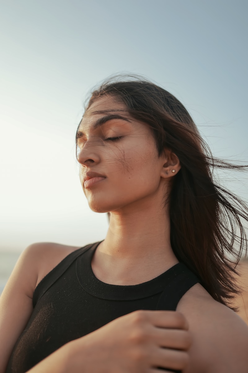 A woman standing on the beach with her eyes closed